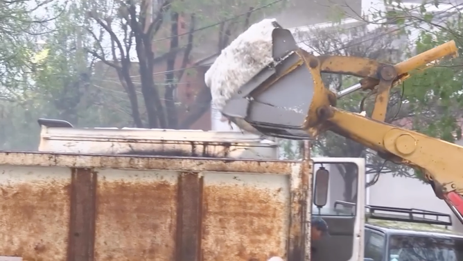 Hail is dumped into a dumpster for removal.